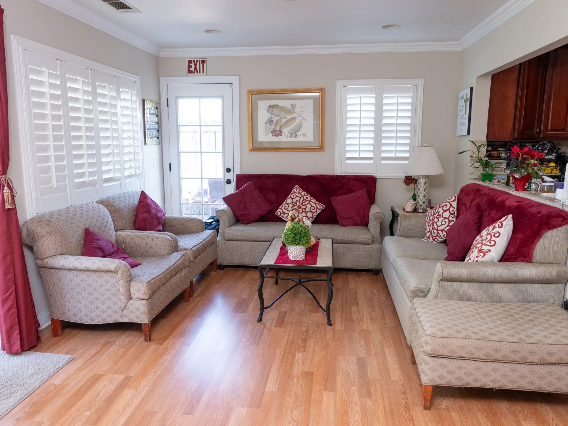 Welcoming common living room area with comfortable seating, natural light, and accessible exit for residents
