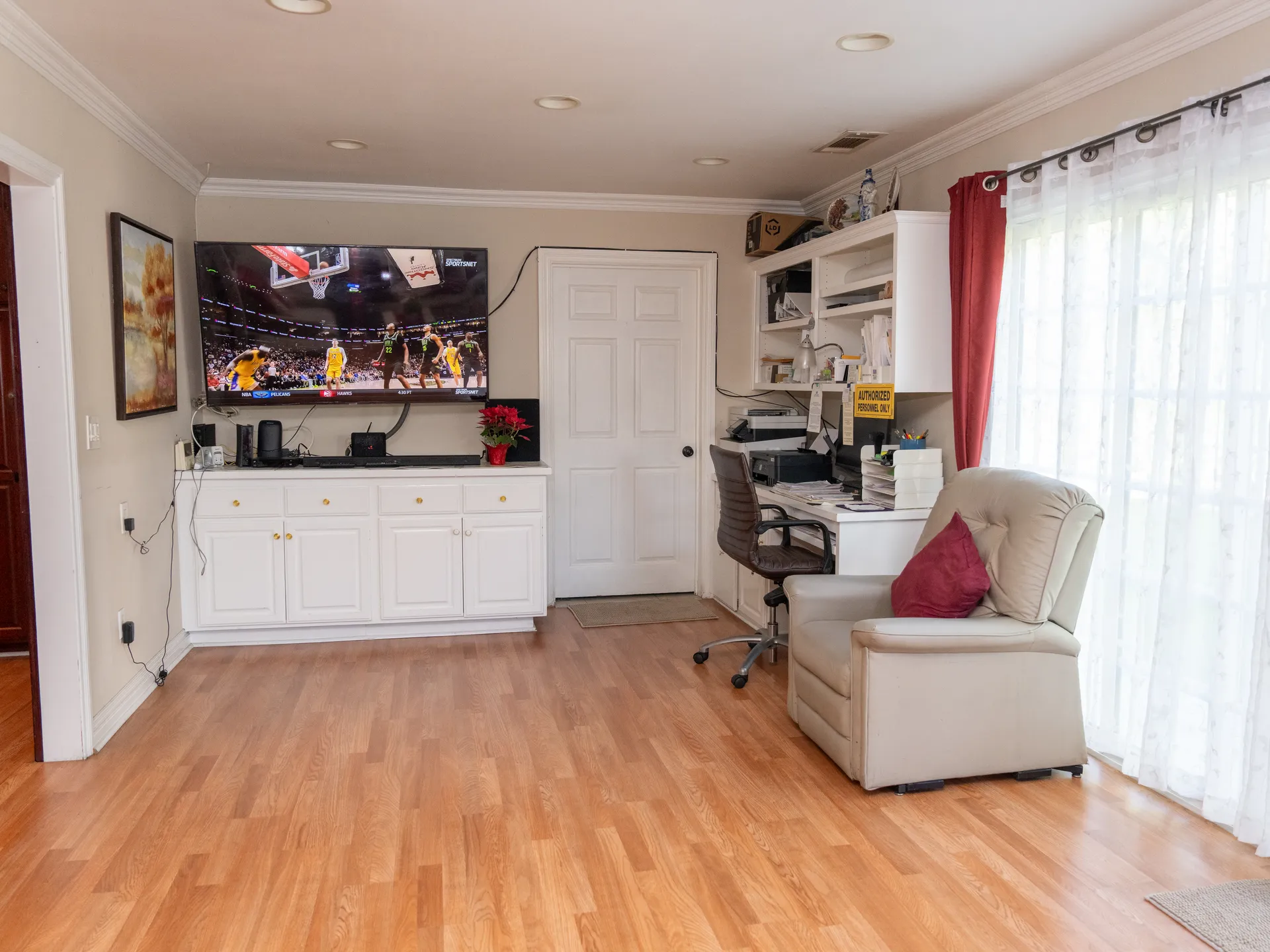 Comfortable multipurpose room with entertainment center, workspace, and seating area featuring accessible layout and warm lighting