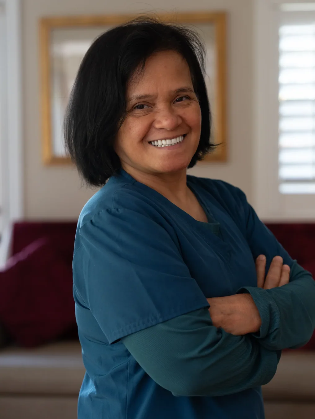 Professional caregiver smiling warmly in medical scrubs at residential care facility